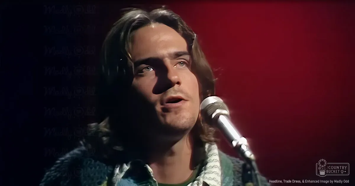 A young adult male in a patterned green shirt sings into a microphone against a red backdrop, likely during a performance or recording session.