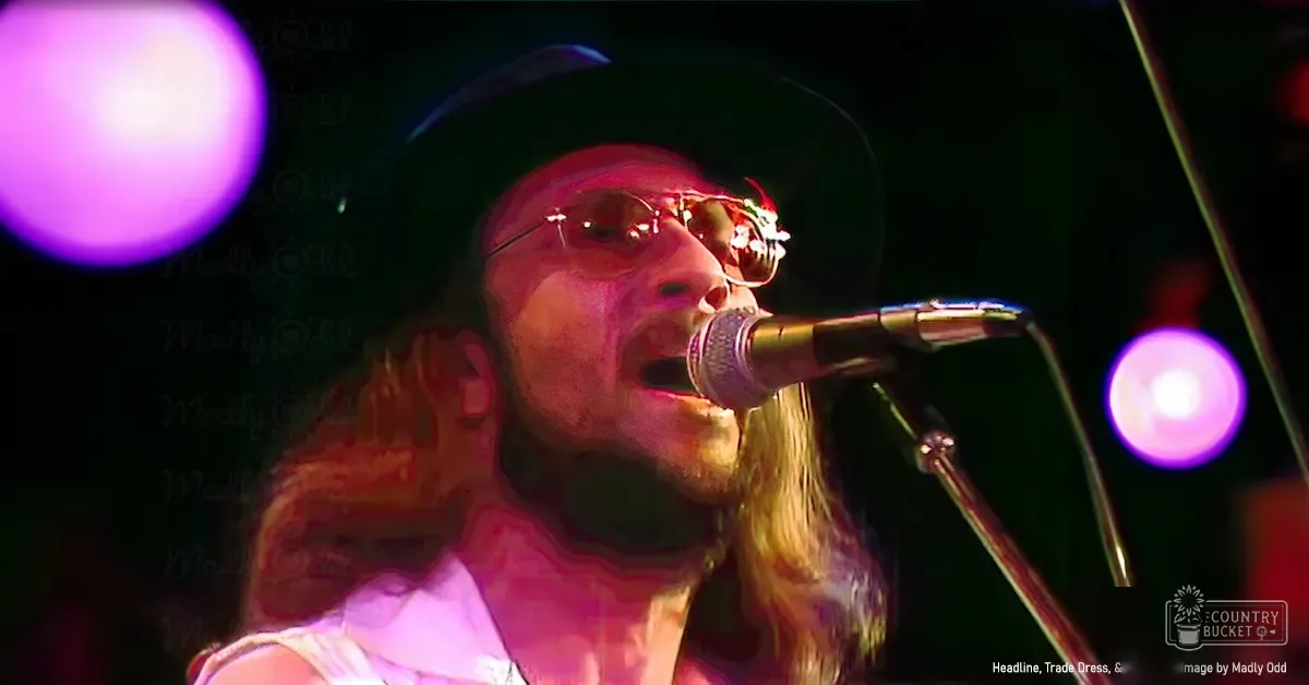 Adult male singer in a white tank top playing guitar at a concert venue with 'Molly Odd' logo visible, stage lighting dominated by purple hues.