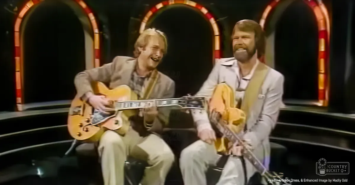 A musical performance scene indoors, with middle-aged male performers in formal attire on a stage with decorative arches and red and gold trim.