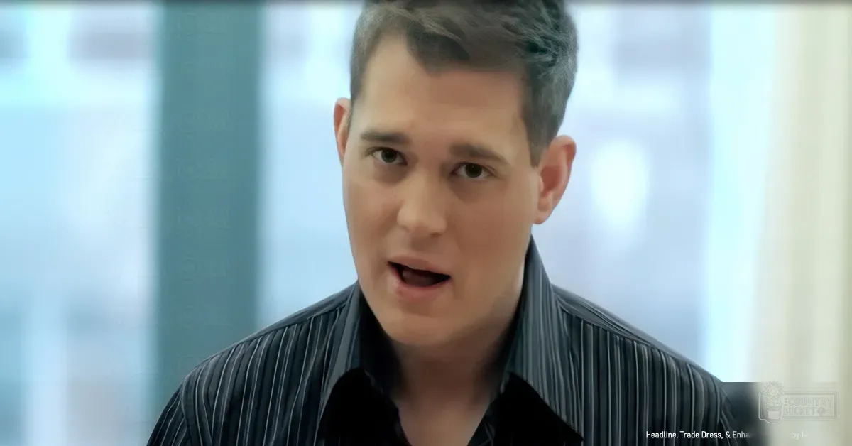 A young adult male wearing a striped button-up shirt in an indoor office setting with natural light streaming through large windows.