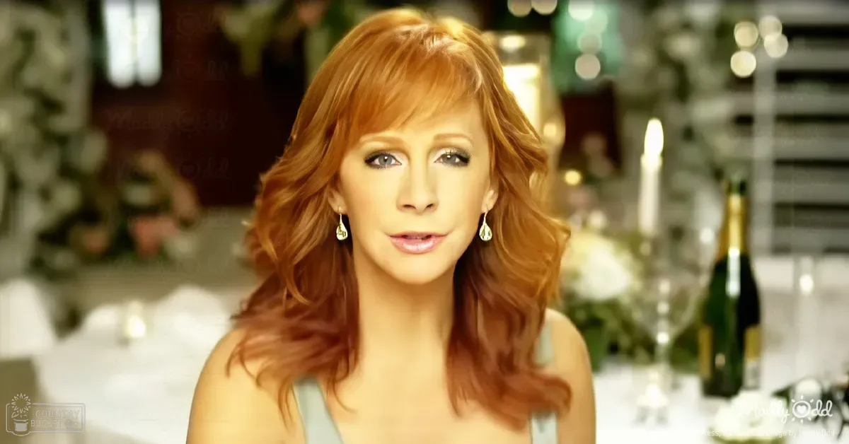 A middle-aged adult female wearing a fitted, sleeveless strapless top or dress with a scoop neckline in light blue or teal, accessorized with teardrop-shaped earrings, seated at a table set for a formal occasion. The setting appears to be an indoor venue decorated for a special event like a wedding or dinner party.