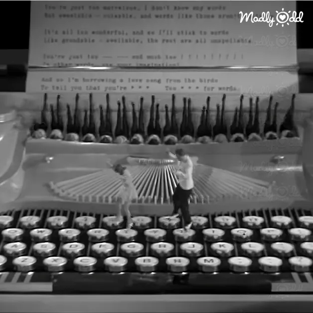 Two individuals standing on a vintage typewriter indoors with sheets of typed text, suggesting an office or study room setting.