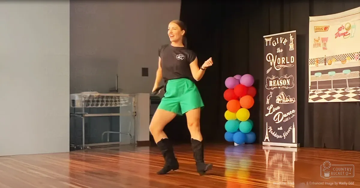 A young adult female dances in a performance space adorned with colorful balloons and a retro diner backdrop, suggesting an indoor dance studio or community center.