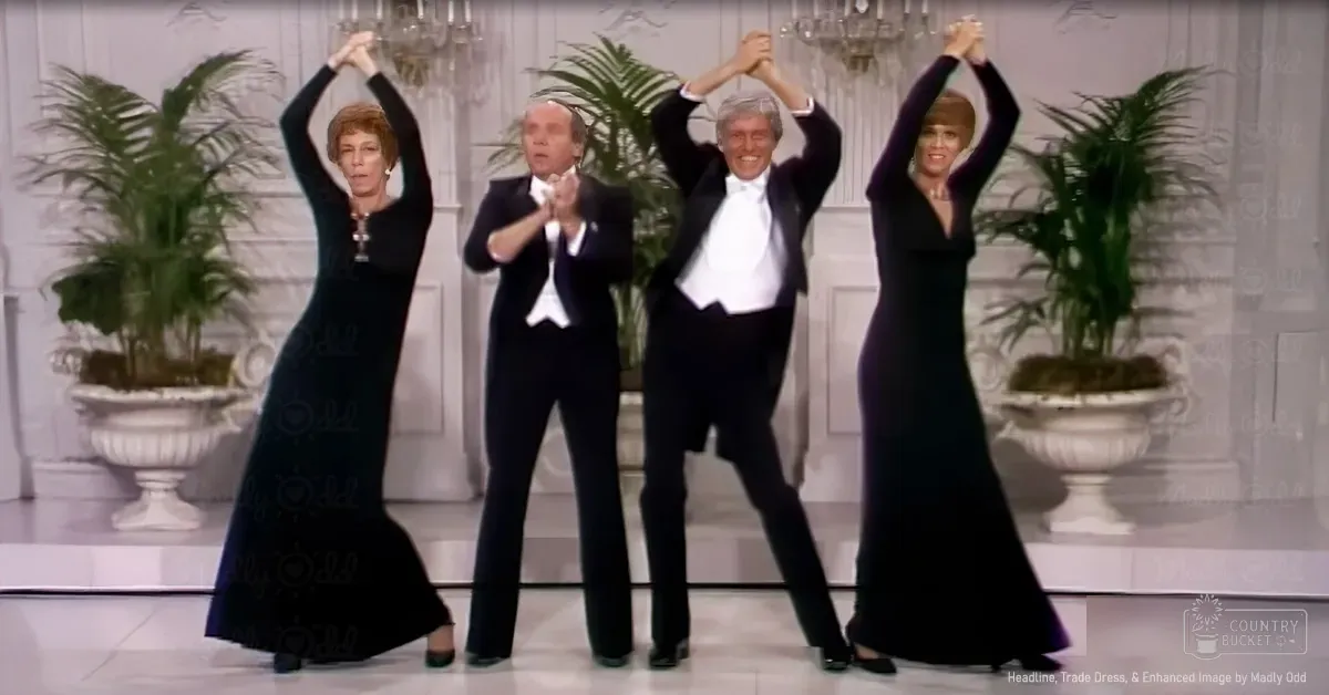 A group performing on a stage or studio with decorative elements, including potted plants and ornate white urns, under bright lighting.