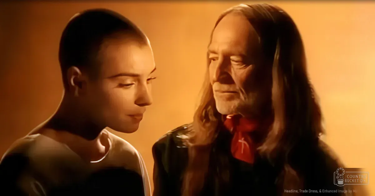 Two young adult males indoors with warm lighting; one wearing a white t-shirt and the other in a black leather jacket over a red shirt.