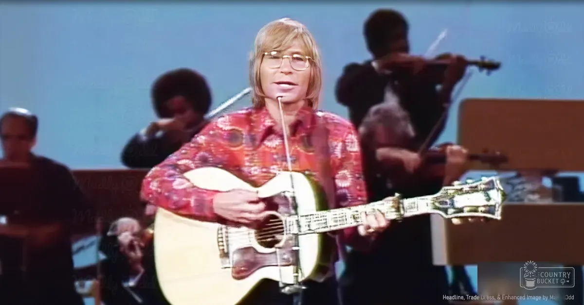An adult male musician wearing a vibrant floral-patterned long-sleeve shirt with glasses, performing on stage or in a studio setting.