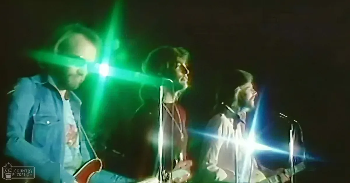 A band performs on stage with bright stage lights creating lens flares.
