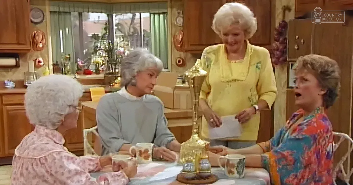 Betty White stands at a kitchen table with three other women, holding a piece of paper, while they all look at it.