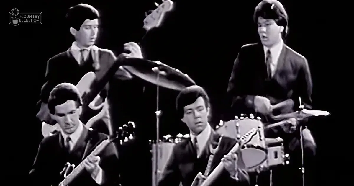 A black-and-white image of a band performing, with musicians playing guitars and drums.