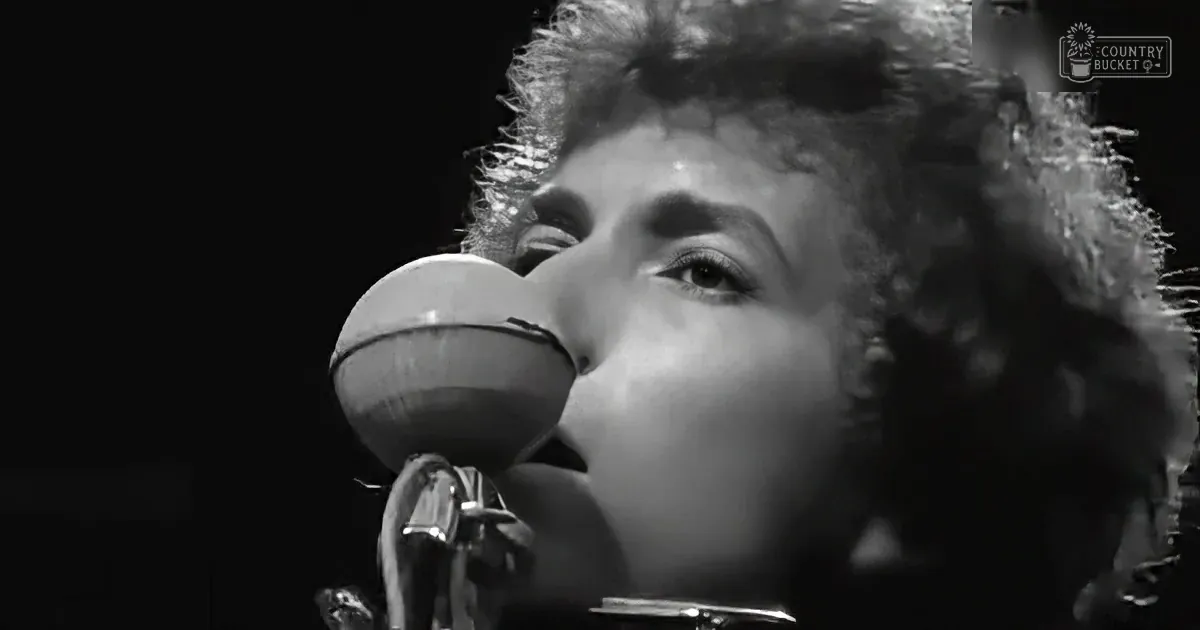 Bob Dylan singing into a microphone, close-up, black-and-white.