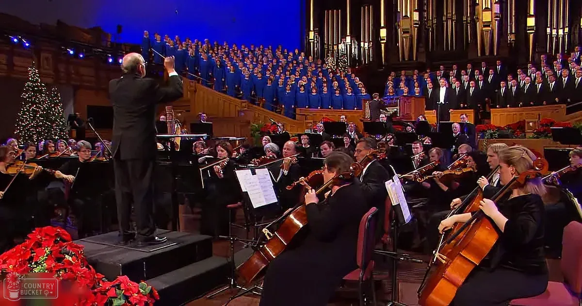 Conductor leads orchestra and choir in a festive performance with Christmas decorations.