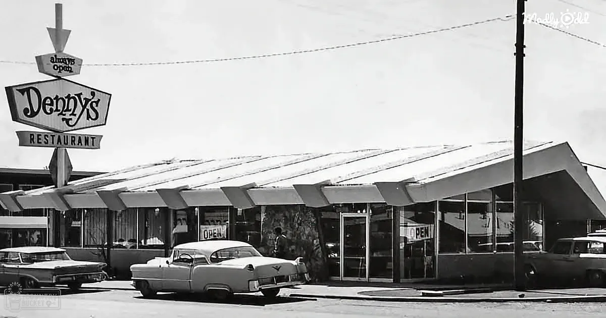 Denny's restaurant sign and building with cars parked in front, vintage style.