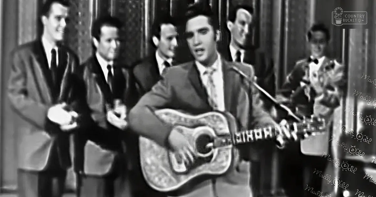 Elvis Presley plays guitar on stage with a band, singing passionately.