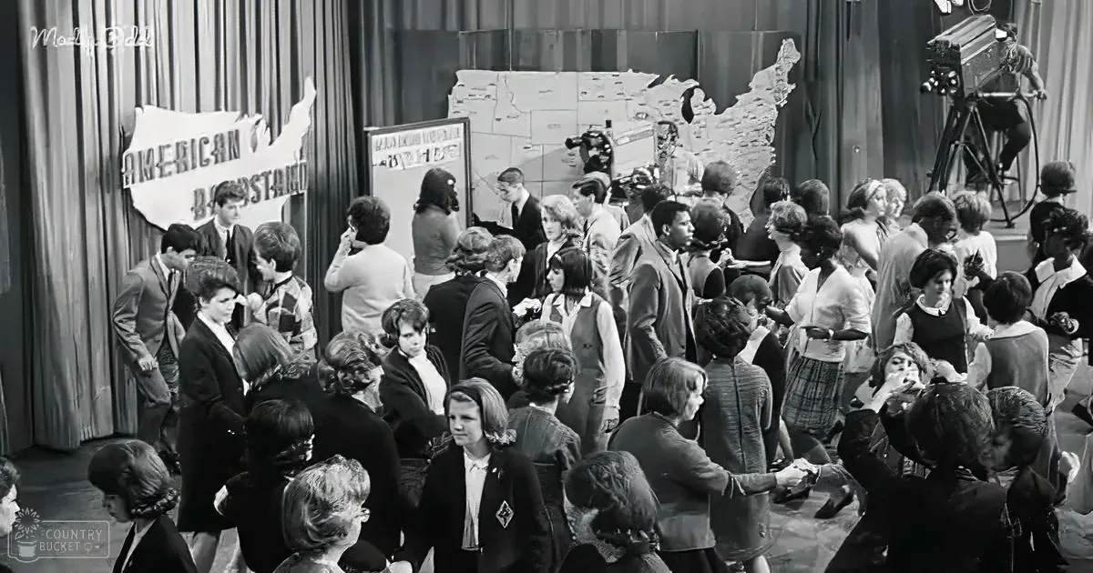 A large group of people, possibly contestants, gather around a map of the United States in a studio setting.
