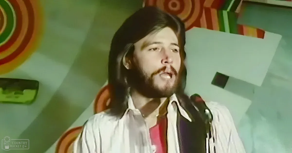 A man with long hair and a beard sings into a microphone, wearing a white shirt with a red tie, against a colorful, retro...