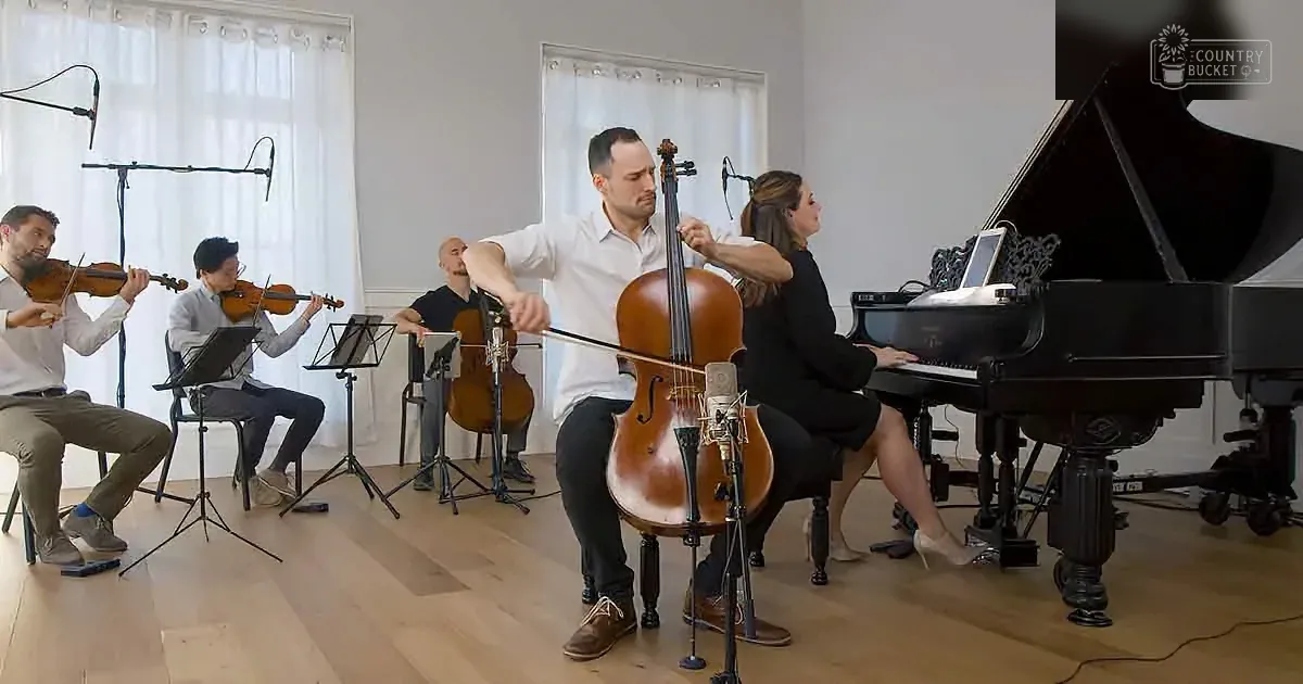 A man plays cello in a small ensemble with violinists, a cellist, and a pianist in a studio setting.