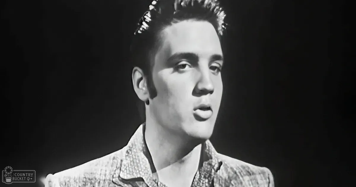 A man with styled hair and a patterned jacket is captured in a black-and-white image.