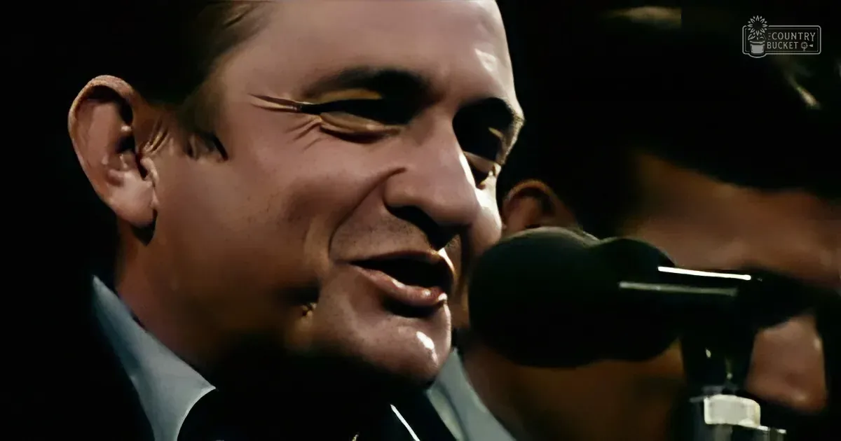 A man in a suit sings into a microphone, his face close to the mic, with another person partially visible behind him.