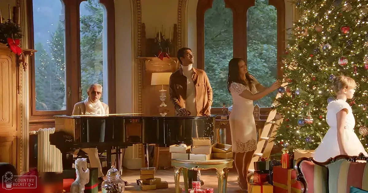 A man in white plays piano as others decorate a Christmas tree in a festive living room.