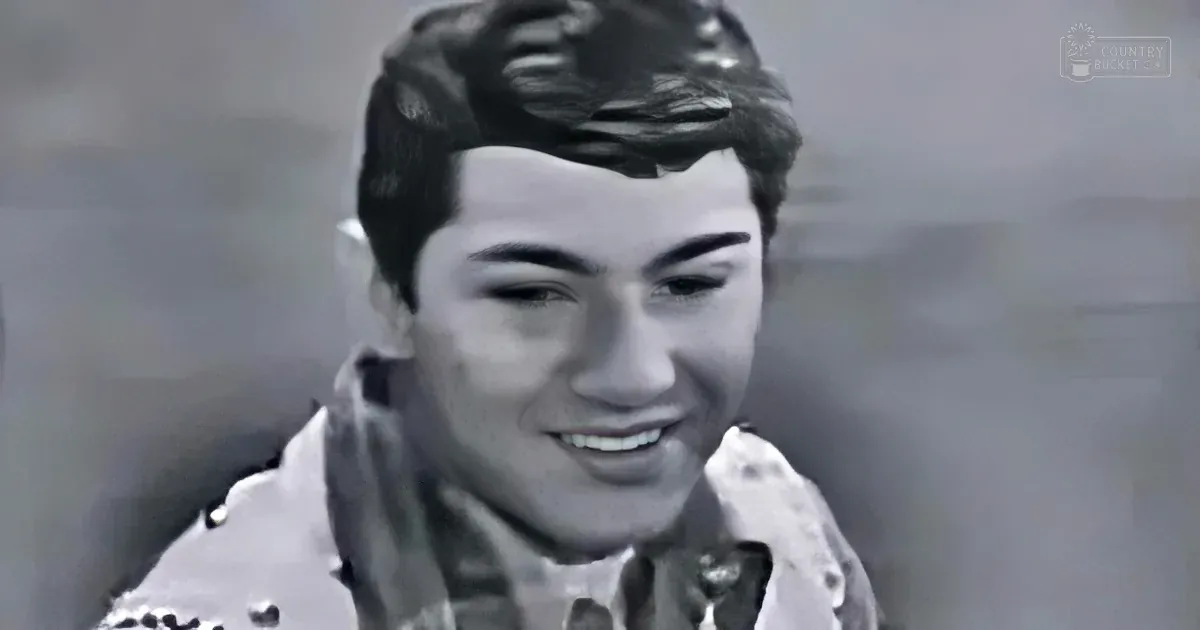 A smiling young man with short, styled hair and a button-up shirt is the main subject.