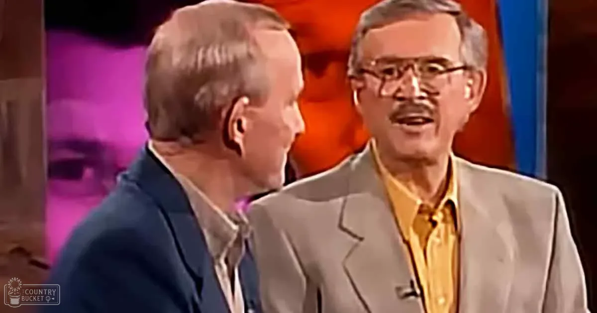 Two men in suits, one in a blue suit and the other in a beige suit with a yellow shirt, appear to be engaged in a...