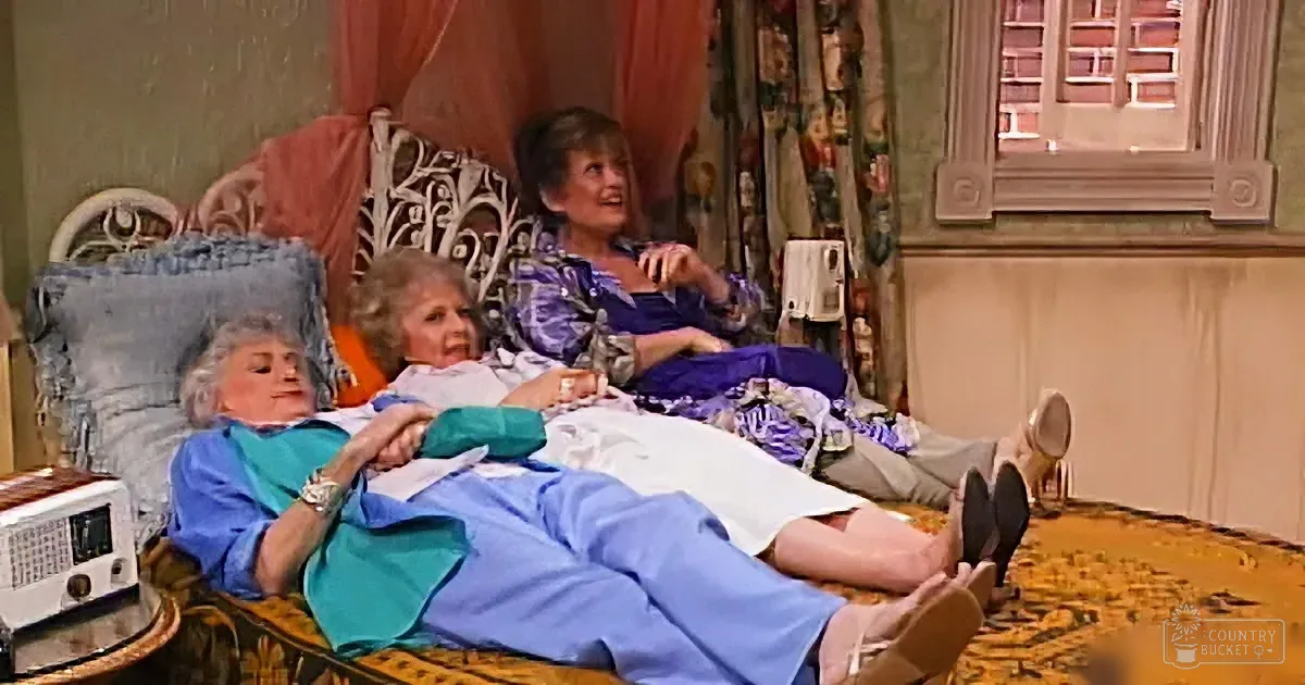 Two women in a cozy living room, one reclining on a chair, the other lying on a couch, both appearing relaxed and engaged...