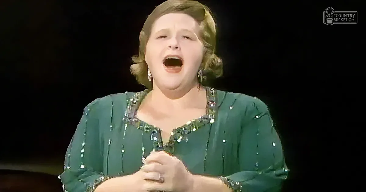 A woman in a green sequined dress sings passionately, holding a microphone.
