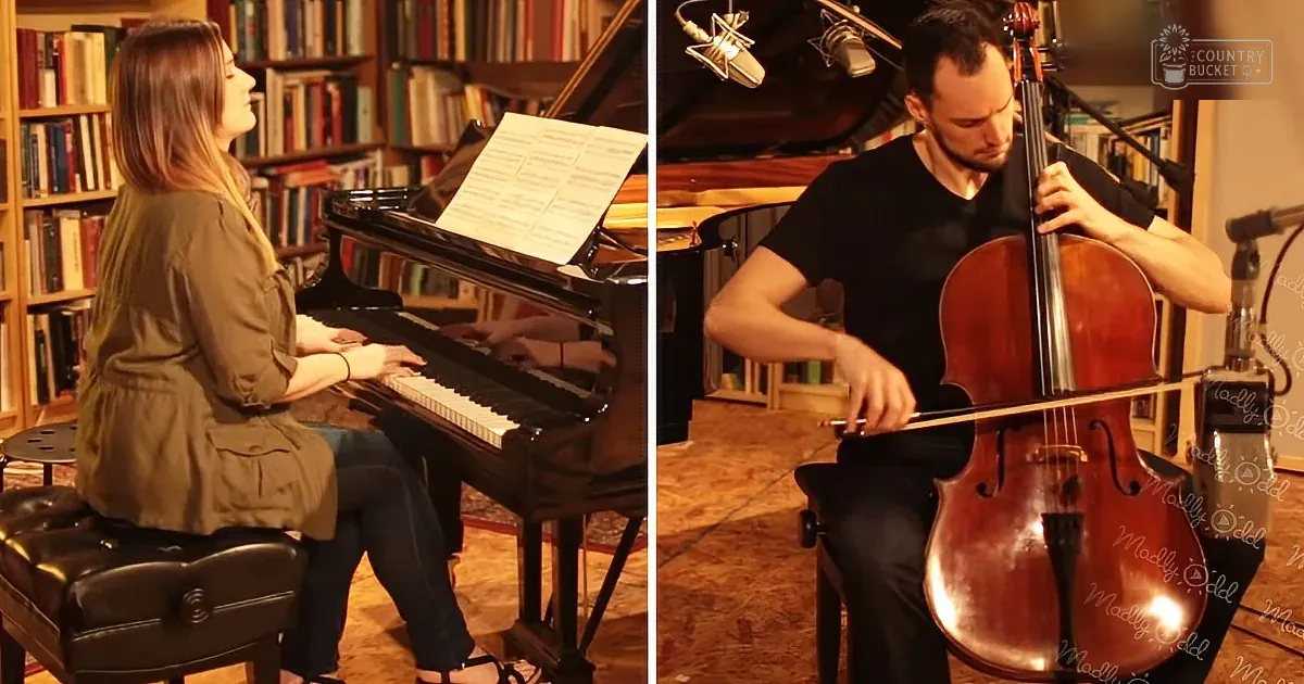 A woman plays piano while a man plays cello in a cozy room with bookshelves.