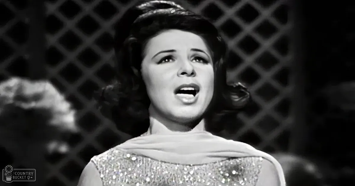A woman in a sparkly dress sings passionately, her mouth open, with a lattice background.