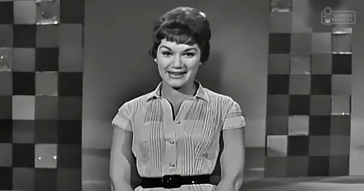A woman in a striped shirt smiles against a checkered background.