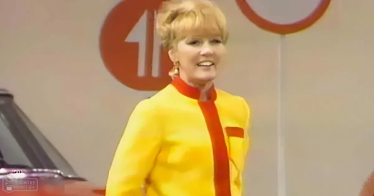 A woman in a yellow outfit smiles in front of a red sign with an arrow.